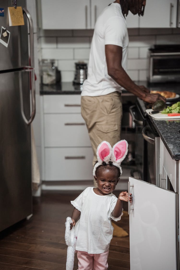 A Child Opening A Kitchen Cabinet