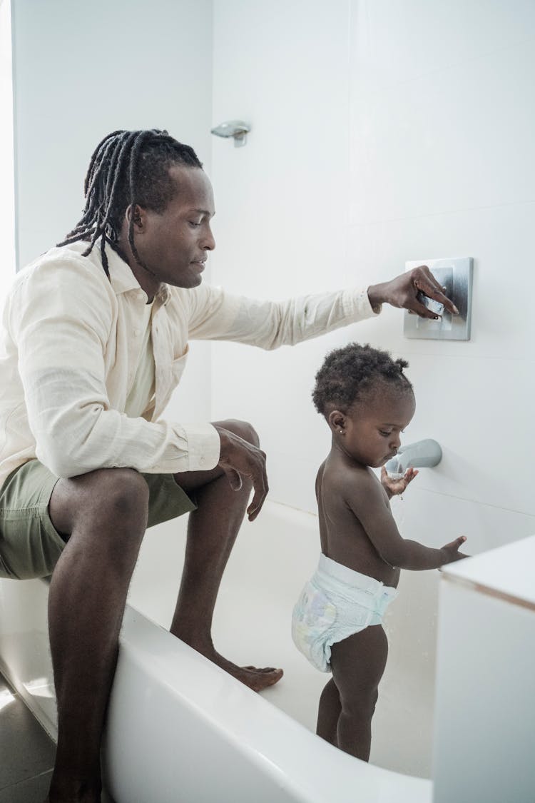 A Child Washing Her Hands While In A Bathtub