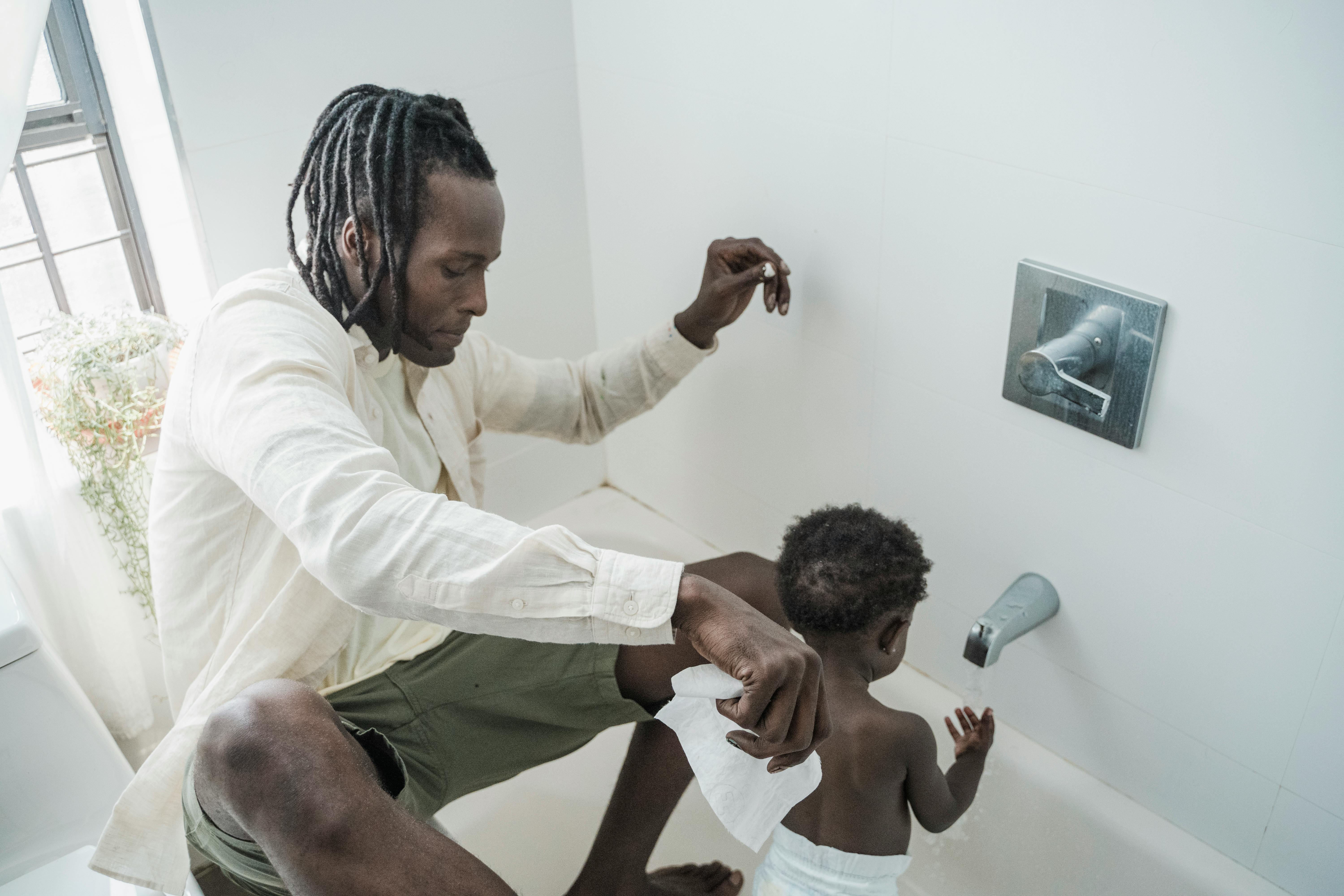 A father lovingly bathes his child in a bright, minimalist bathroom setting.