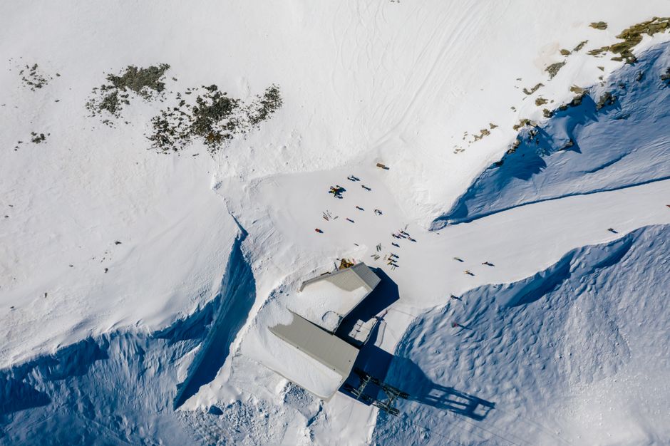 A stunning aerial view capturing a snowy mountain landscape with a ski lift and skiers.