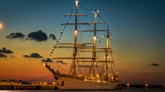 令人惊叹的日落时分，一艘宏伟的帆船停靠在港口，照亮了宁静的海景