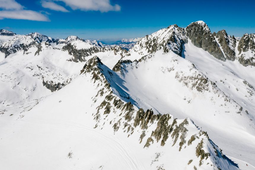 Aerial view of snow-covered mountain peaks under a blue sky. Photo by Mikhail Nilov on Pexels