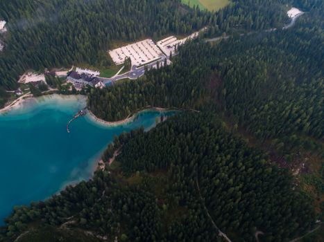 Drone shot of a resort surrounded by lush forest and a turquoise lake, perfect for vacation.