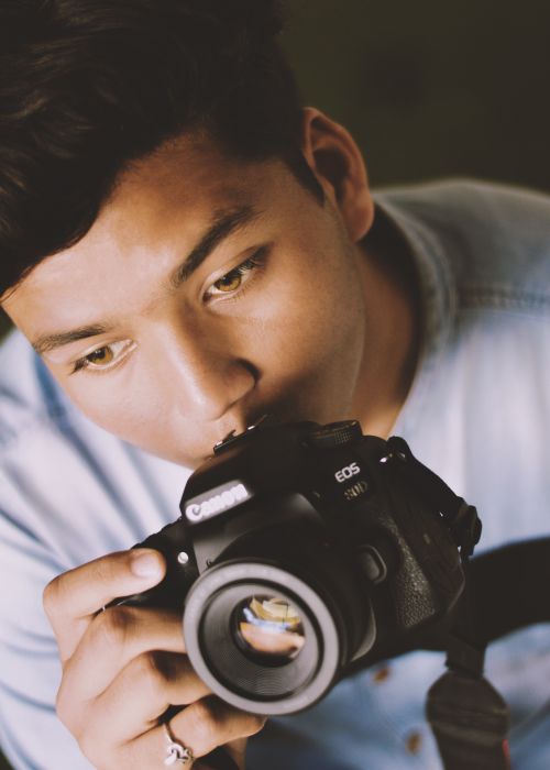 Free A close-up of a focused photographer holding a DSLR camera, showcasing professional equipment. Stock Photo