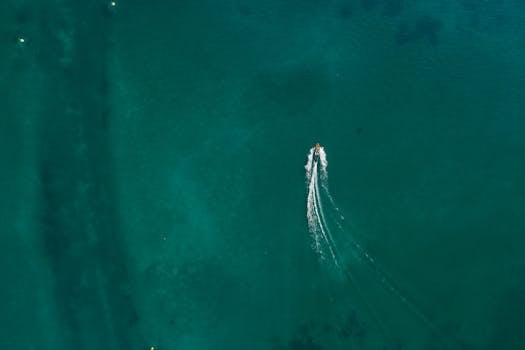 An aerial shot capturing a lone jet ski creating waves on a vast expanse of blue sea.