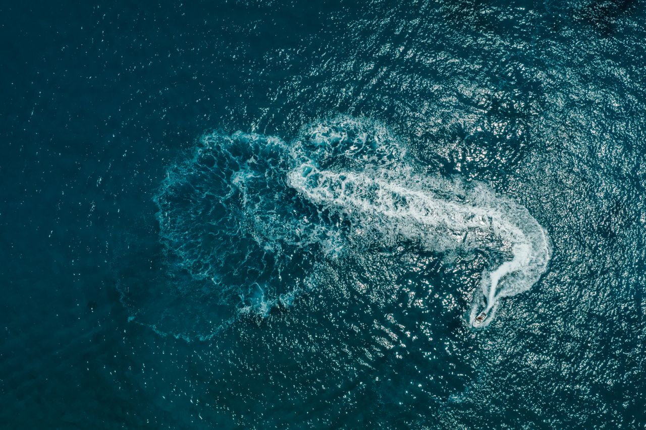 dynamic aerial capture of a jet ski leaving a swirling white trail on