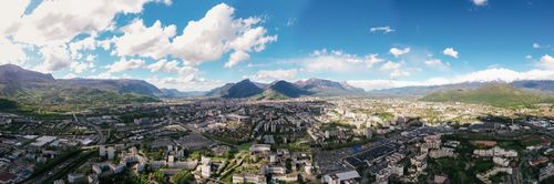 Free A breathtaking aerial view captures a vibrant city nestled between majestic mountains under a clear blue sky. Stock Photo