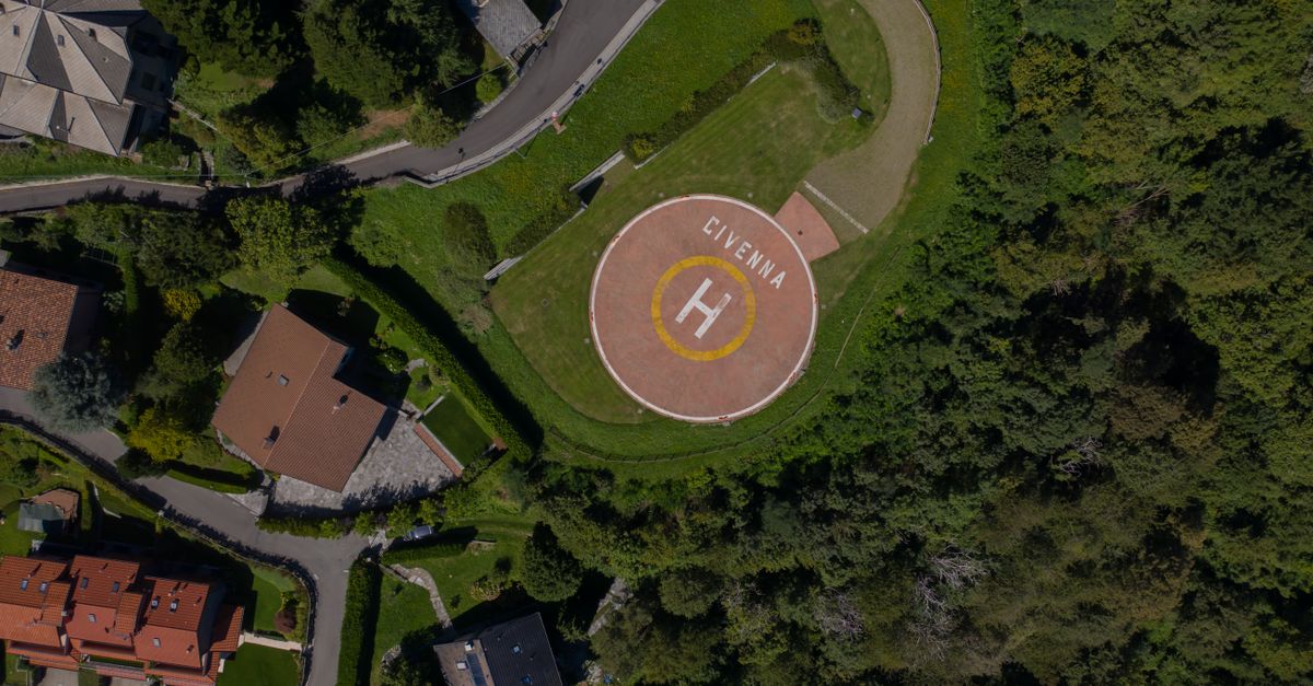 Drone shot capturing a helipad in Civenna surrounded by greenery and residential houses.
