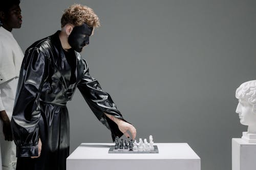 Man in Black Leather Jacket Standing Beside White Table