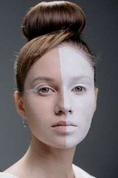 Creative portrait of a woman with half her face painted white, showcasing unique art and style.
