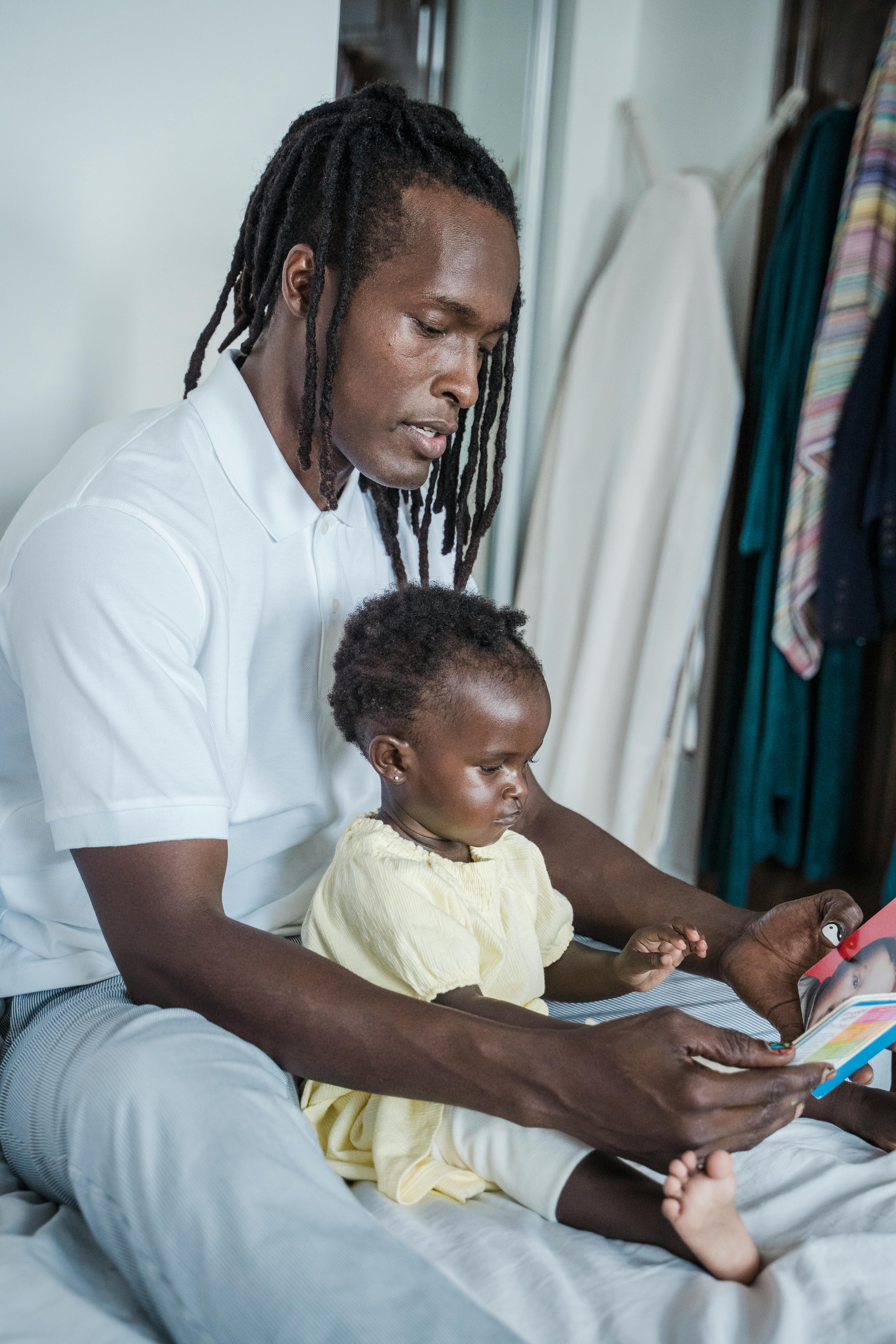 Free Tender moment of father and baby reading a book together indoors. Stock Photo
