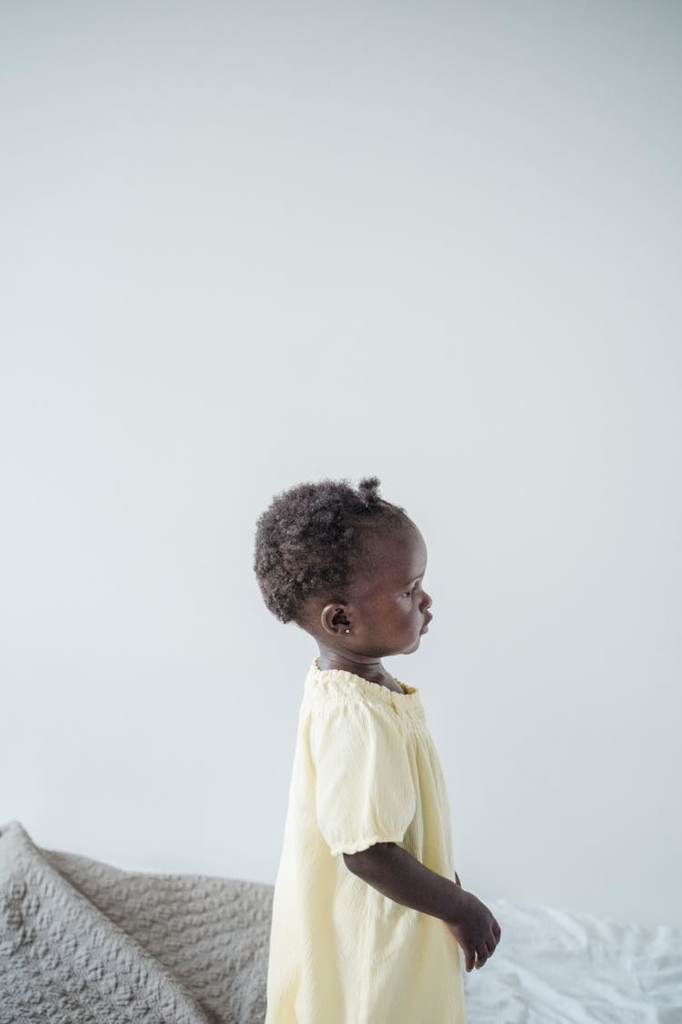 Side View Of A Baby Standing On The Bed