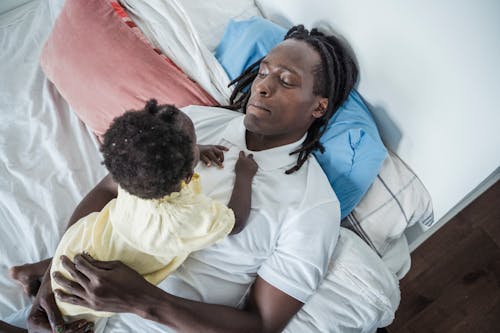 Free High-Angle Shot of a Father and His Child Lying on the Bed Stock Photo