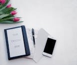 工作空间布局平坦，配有郁金香、笔记本、钢笔和智能手机，非常适合设计