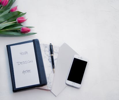 工作空间布局平坦，配有郁金香、笔记本、钢笔和智能手机，非常适合设计