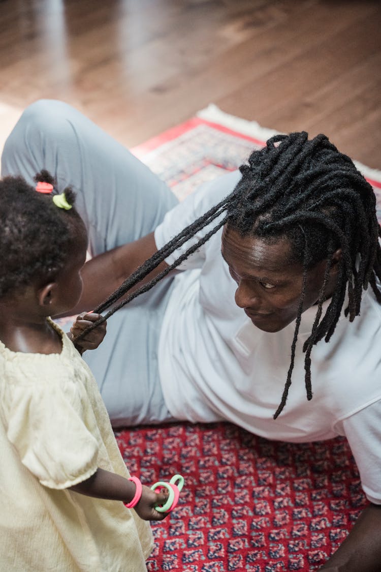 Baby Girl Playing With Fathers Hair On A Pink Carpet