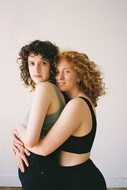 Two women embracing and smiling in a bright indoor setting, showcasing affection and happiness.