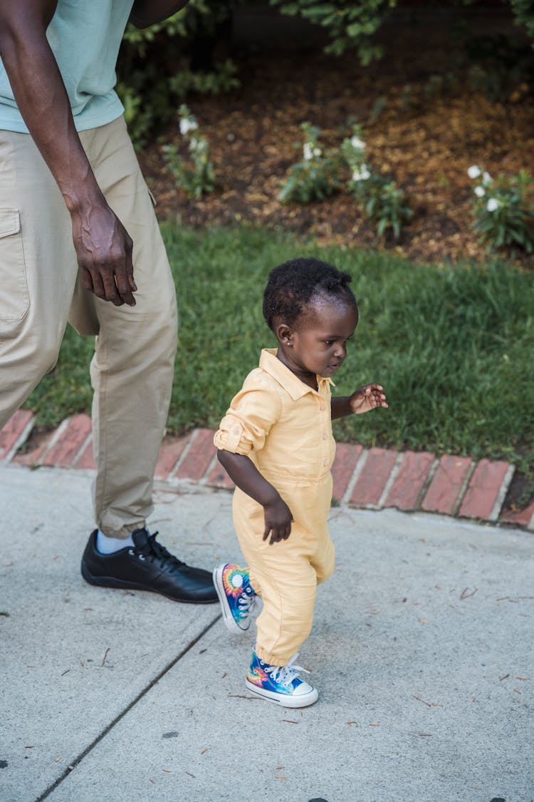 Father Watching His Little Daughter Learning To Walk 