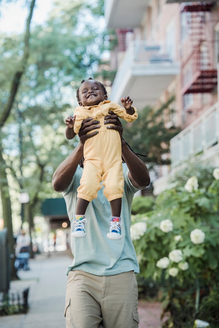 Man Walking Down The Street And Lifting His Baby 