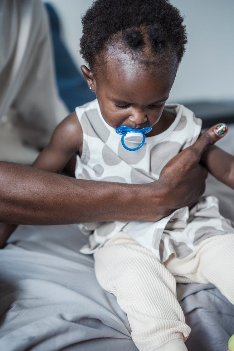 A Toddler With A Pacifier In The Mouth