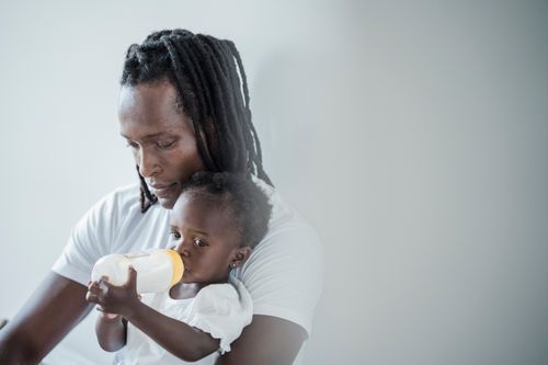 Free A father lovingly cradles his daughter while she drinks milk from a bottle. Stock Photo