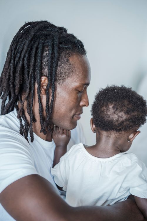 Free A heartwarming moment of a father with dreadlocks holding his young daughter. Stock Photo