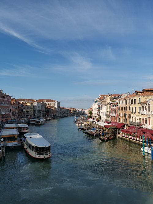 Free Charming view of Venice's Grand Canal with gondolas and historic buildings under a clear blue sky. Stock Photo
