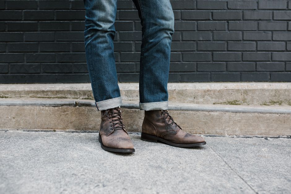 Casual fashion featuring brown leather boots and denim jeans in an urban setting.
