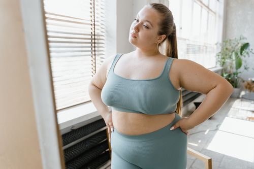 Free A plus-size woman in activewear poses confidently indoors with hands on her waist. Stock Photo