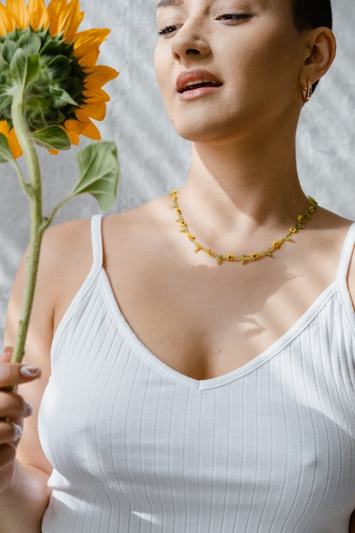 Woman in White Tank Top Holding a Sunflower