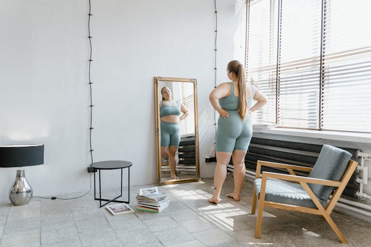 Woman Standing In Front Of A Mirror Near A Window