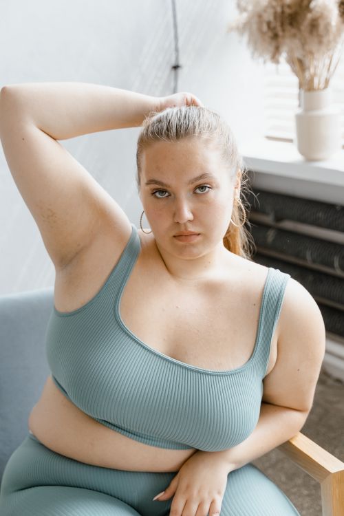 Free Portrait of a confident plus size woman posing indoors in trendy sportswear, promoting body positivity. Stock Photo