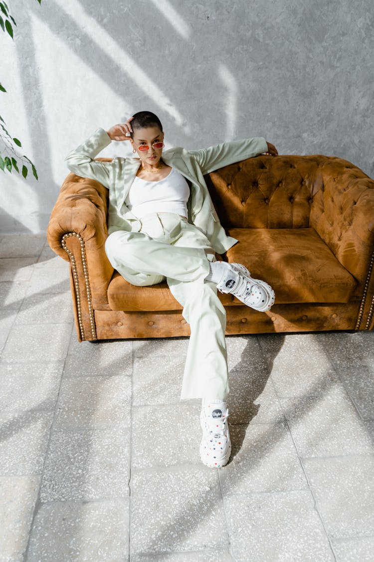 Woman In White Outfit Sitting On Brown Couch