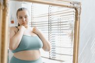 Woman in Teal Bikini Top and White Panty Standing Near Window