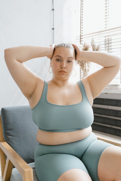 Woman in Teal Sports Bra Sitting on Gray Chair