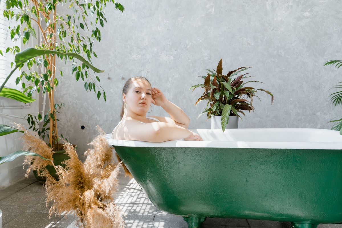 Frau entspannt in einer grünen Badewanne mit Pflanzen in einer ruhigen Home-Spa-Atmosphäre