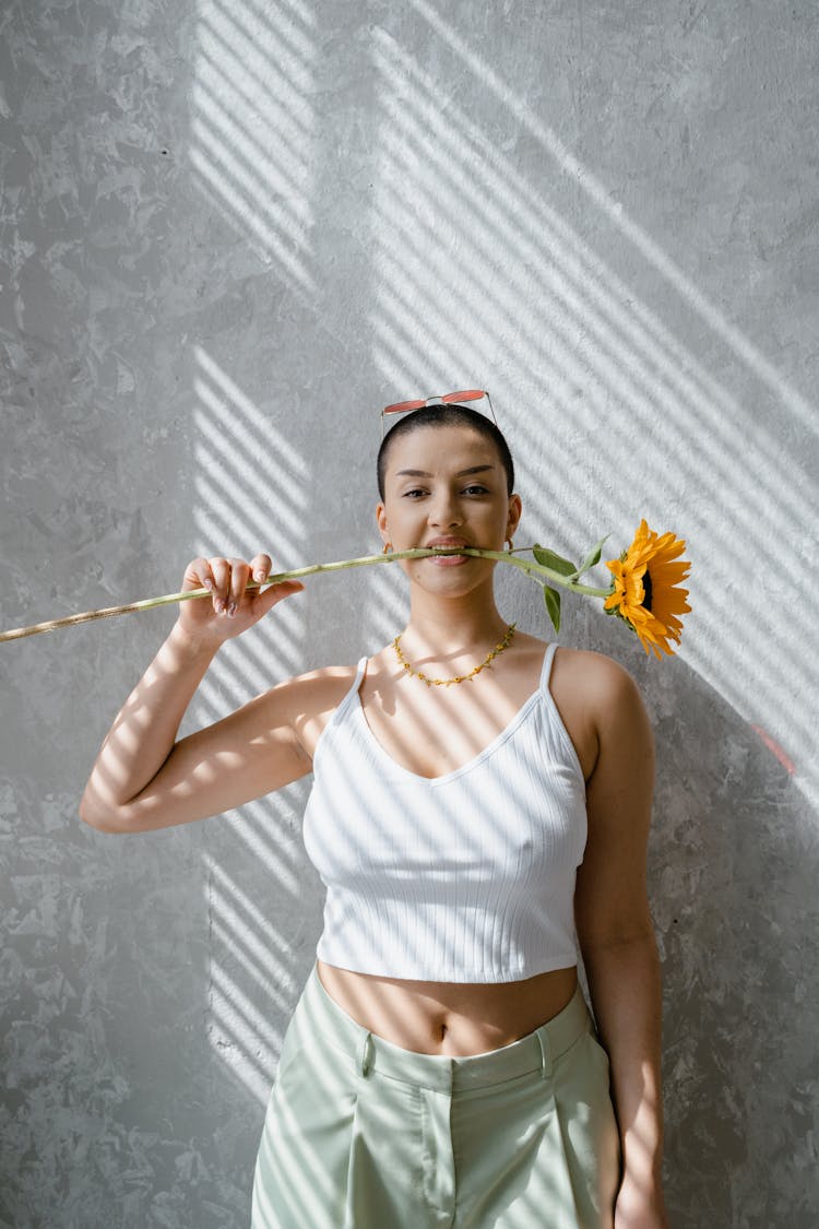 A Woman In White Tank Top Holding A Sunflower