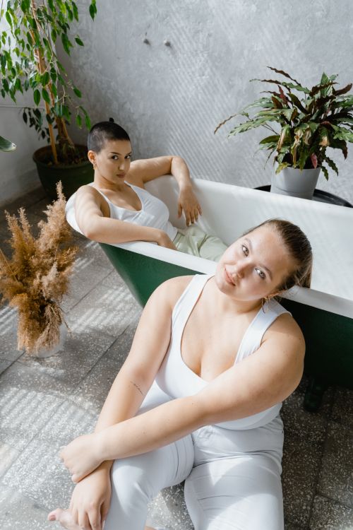 Free Two confident and serene plus-size women relaxing indoors, embracing body positivity. Stock Photo