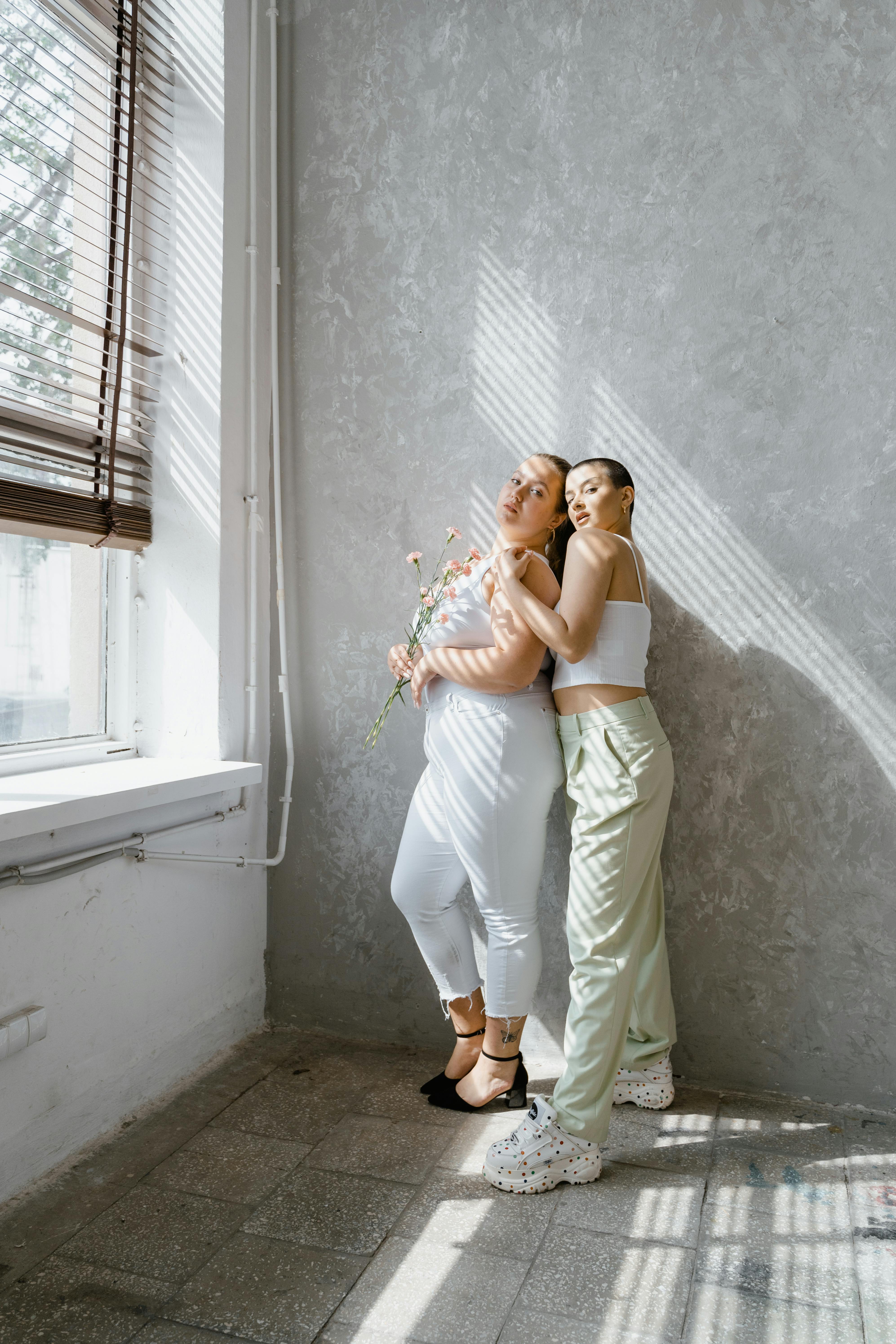 women in white tank top standing beside the window