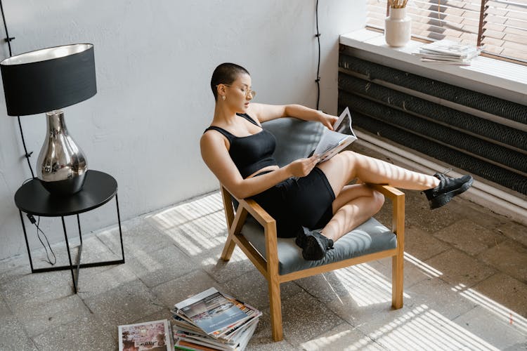 Woman Sitting On Chair While Reading A Magazine