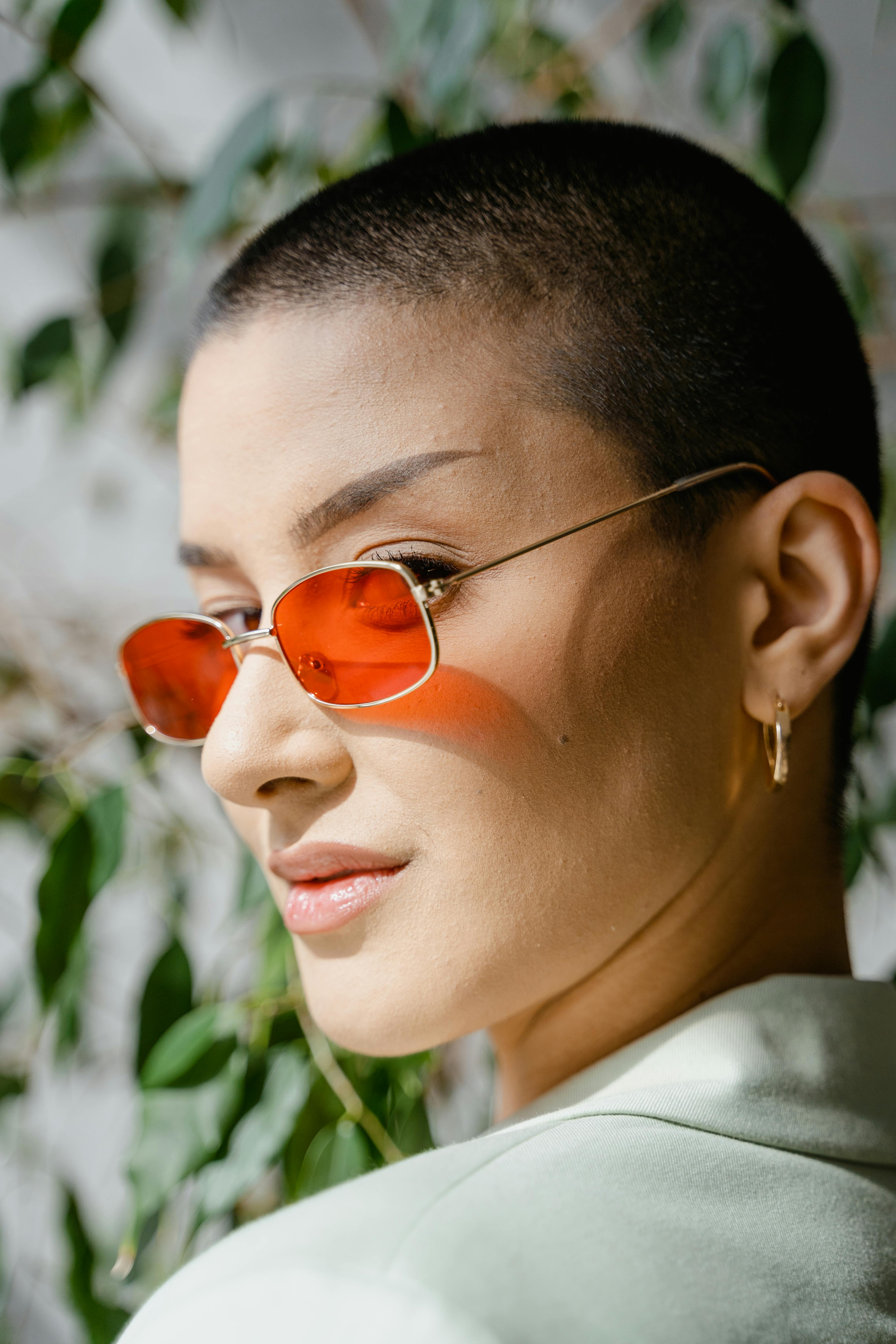 Portrait of a fashionable woman wearing red sunglasses outdoors in natural light.