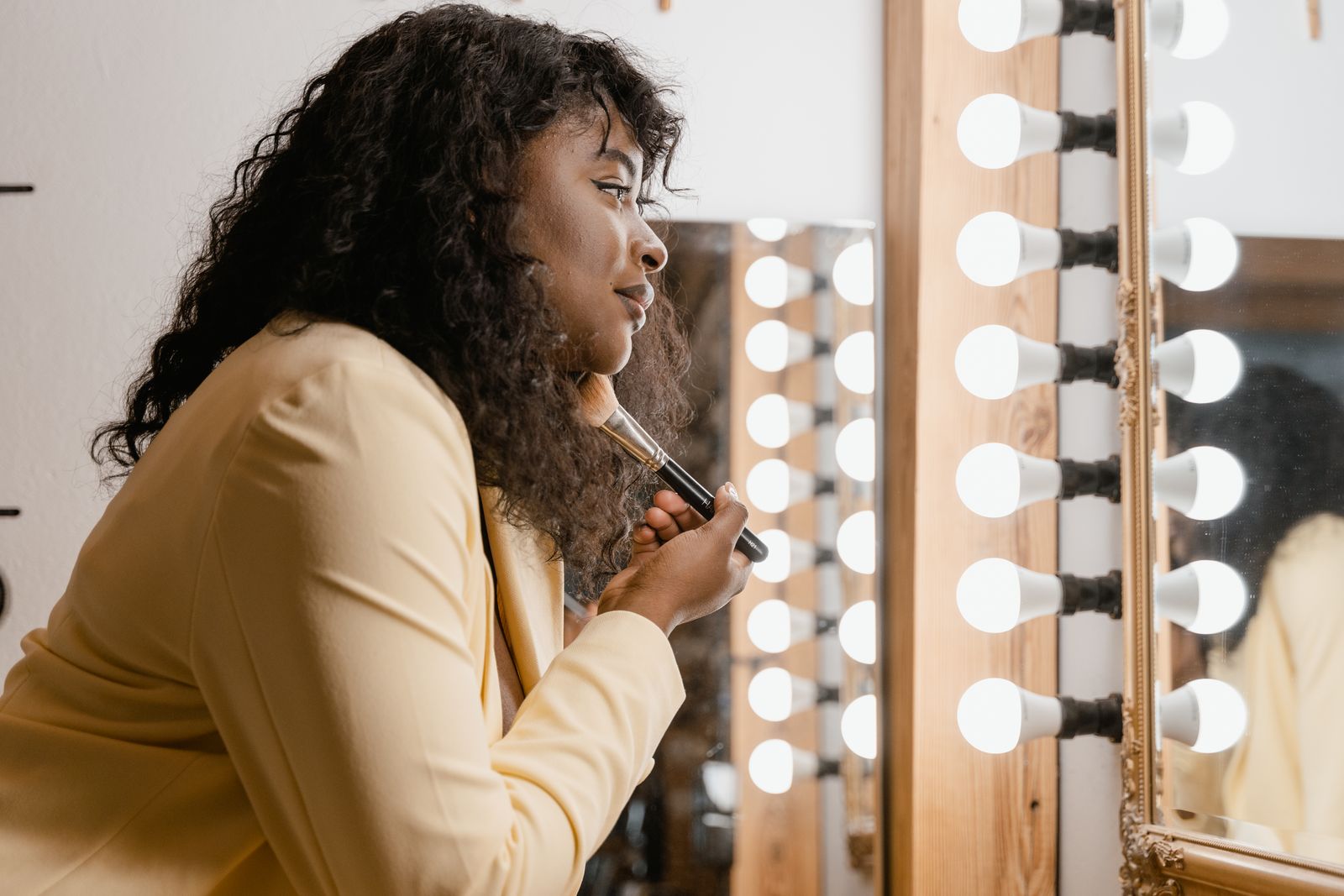 Woman using a makeup brush at a vanity during her beauty routine