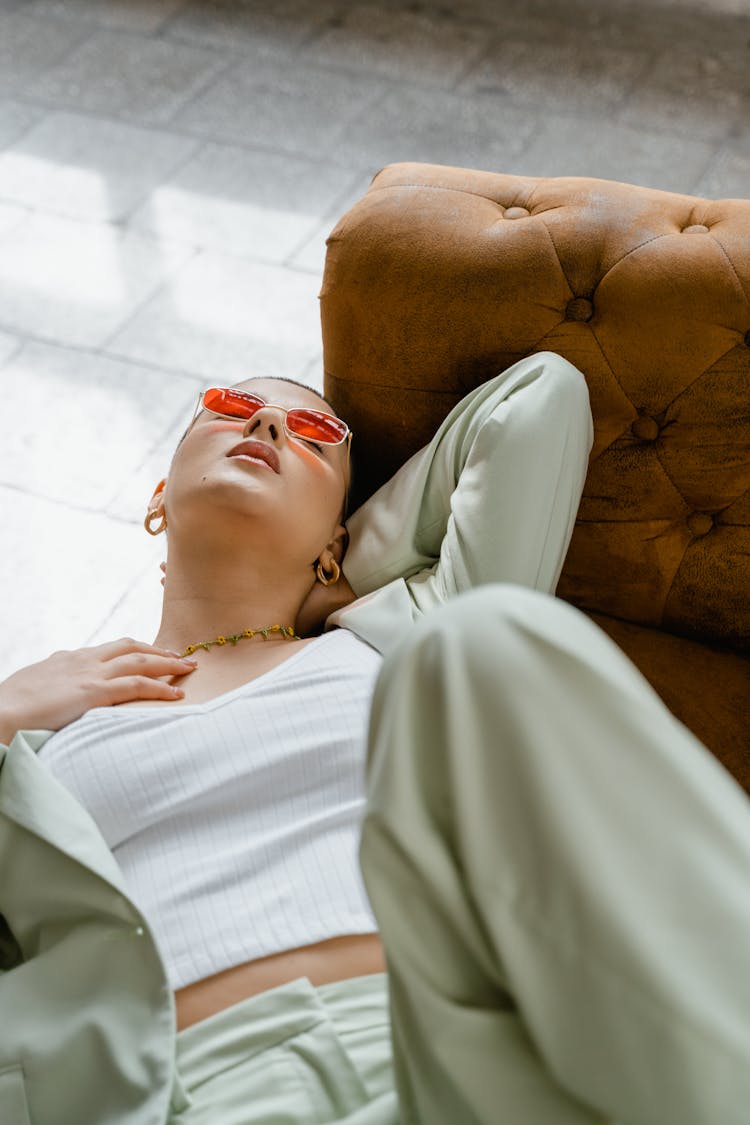 Woman In Sunglasses Lying On Brown Couch