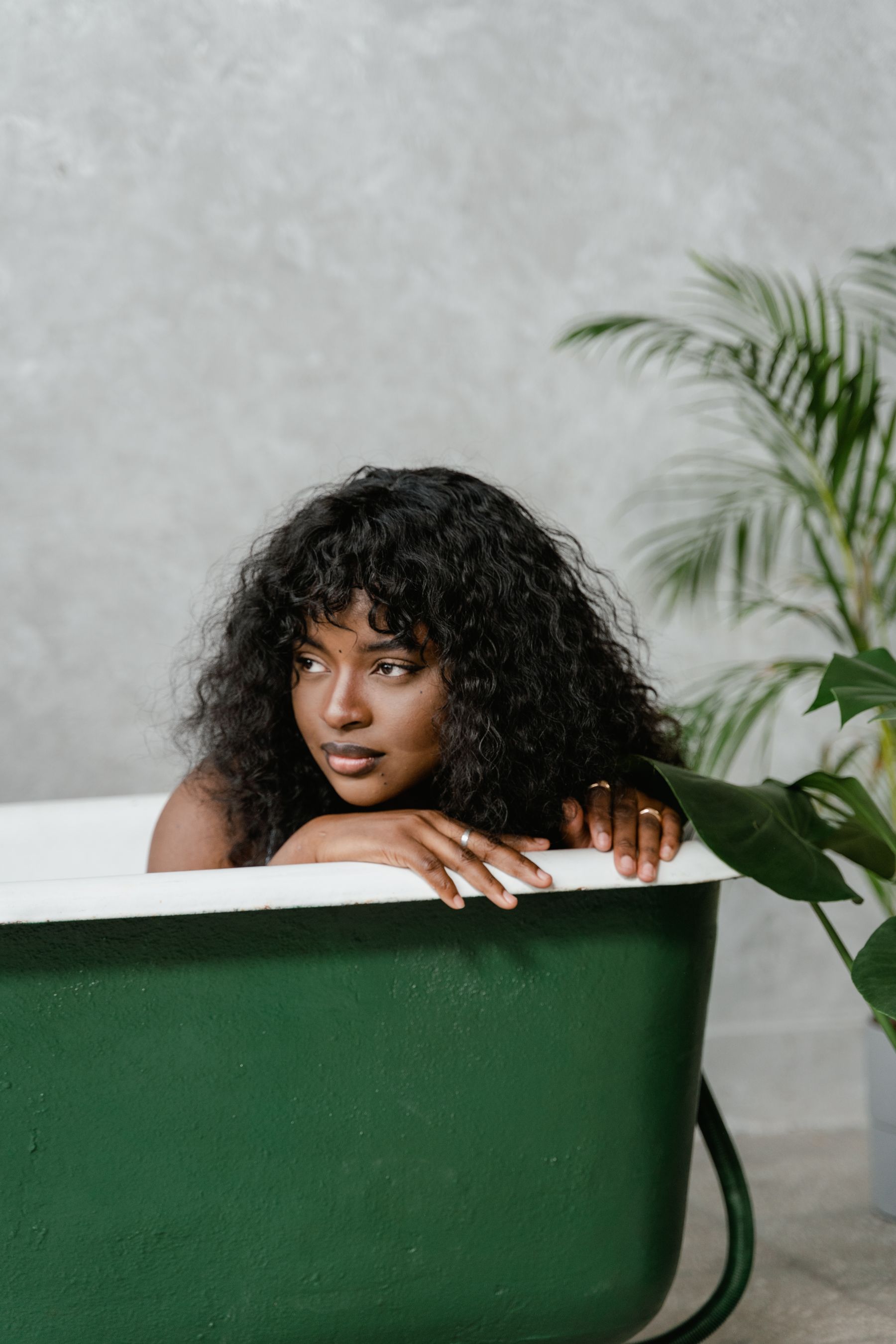 Green bathtub acting as a concentrated focal element among pale surroundings and plants