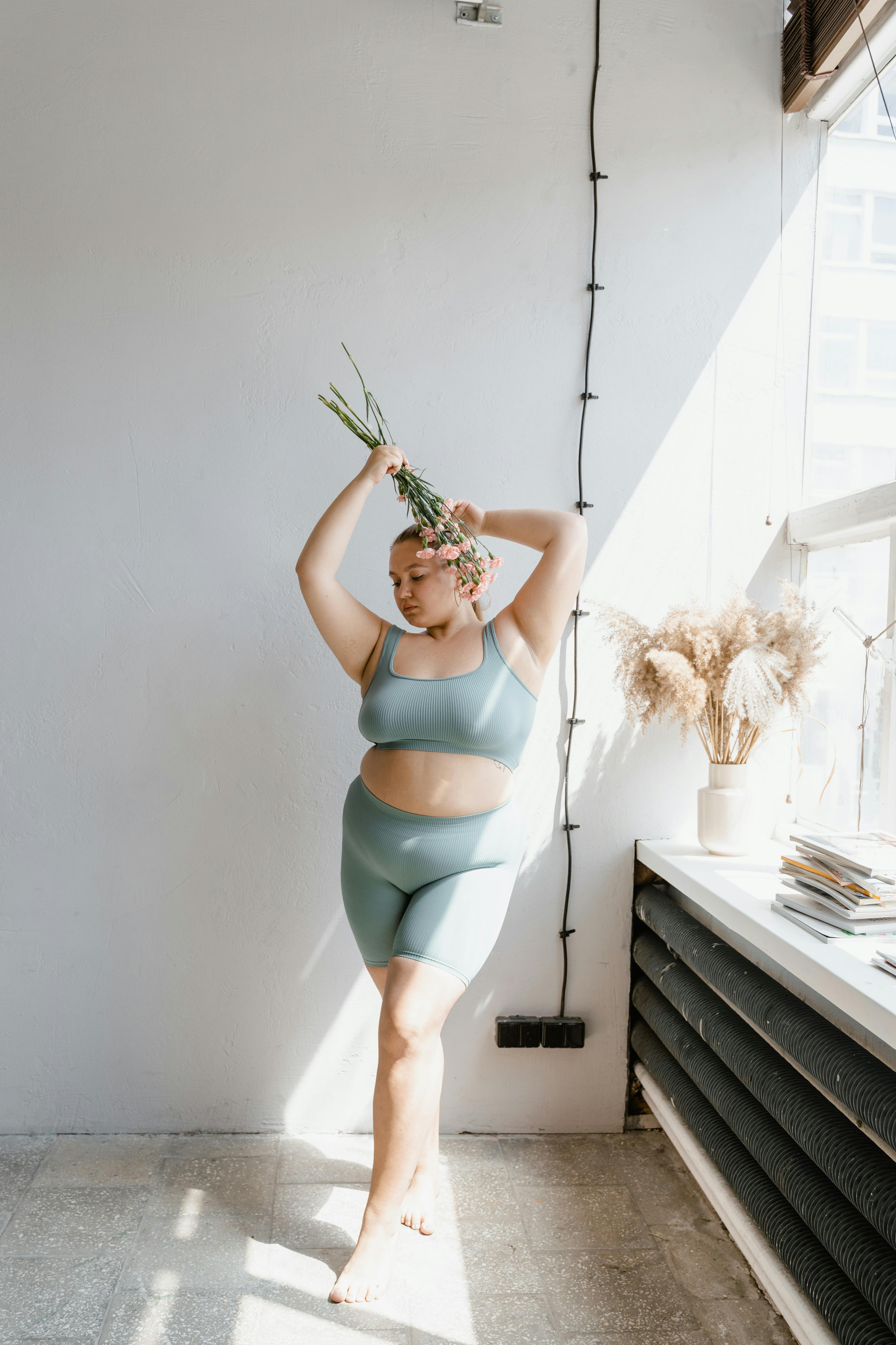 woman in teal brassier standing beside white wall