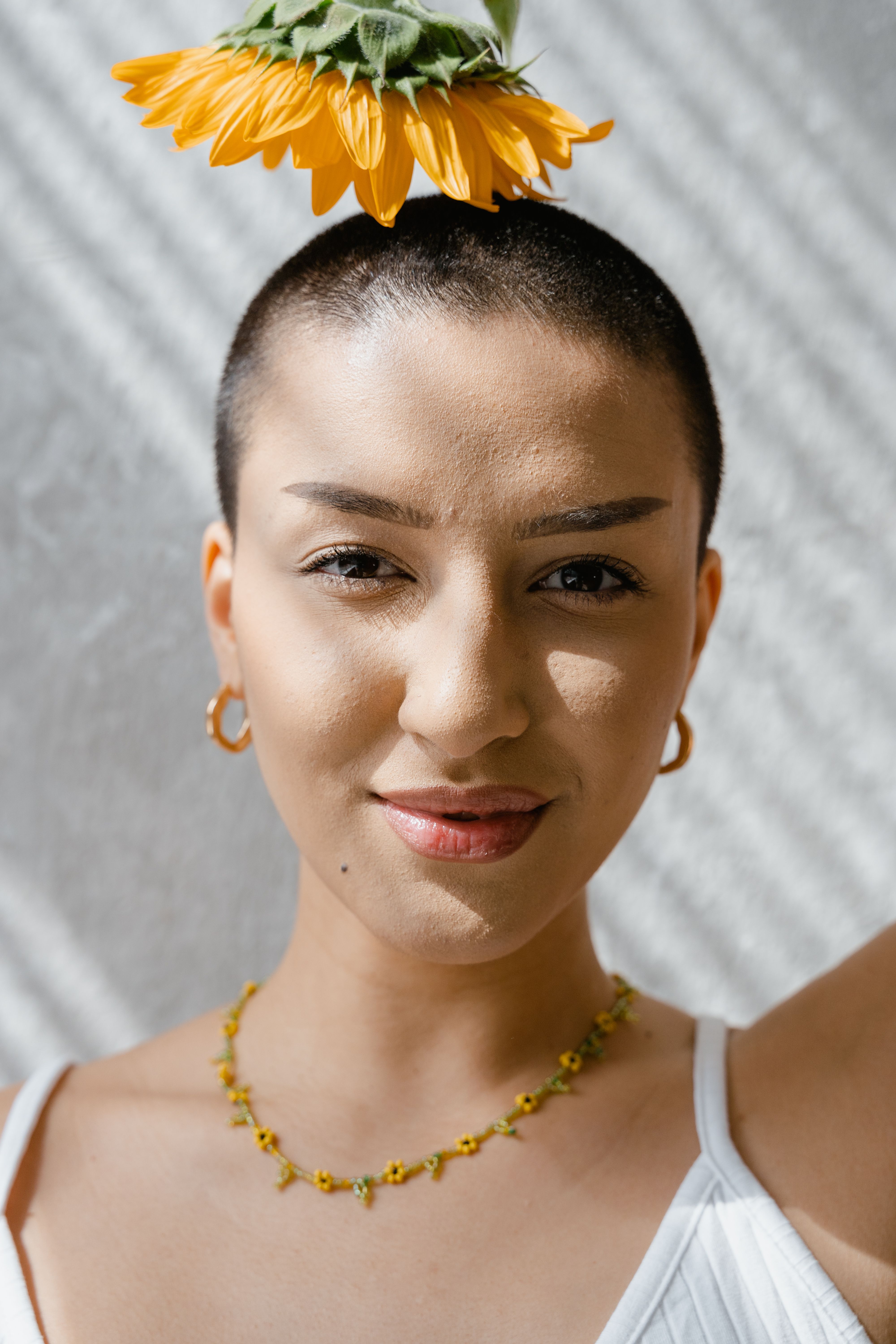 Close-up portrait of a woman wearing a sunflower as a hair accessory, showcasing natural beauty.