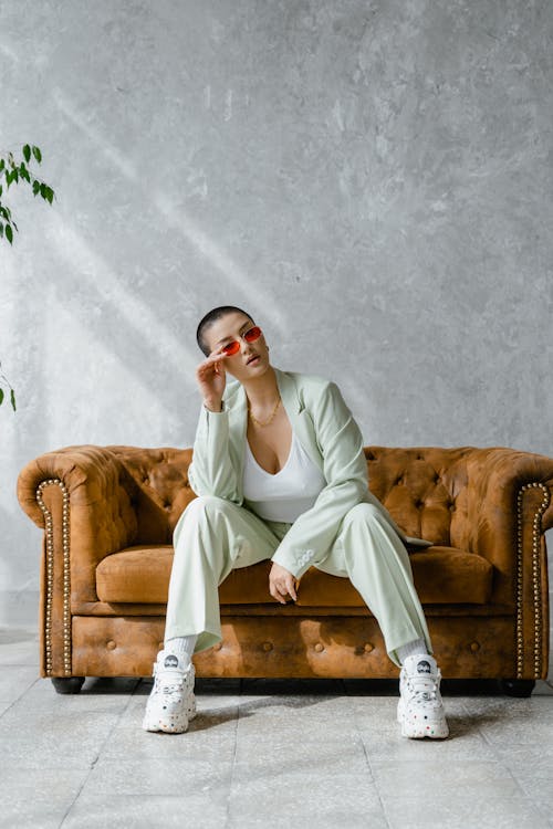Free Woman Holding Her Sunglasses While Sitting on Sofa  Stock Photo