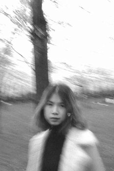 Engaging black and white portrait of a woman with a creative motion blur effect, outdoors.