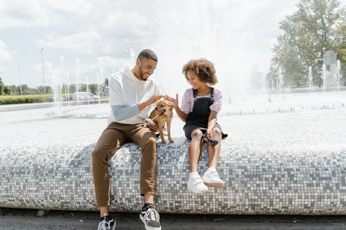 A Man and a Young Girl Sitting Together with Pet Dog