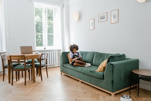 Free Girl Writing on a Notebook While Lying on Sofa  Stock Photo